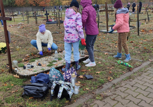 Uczniowie porządkują groby.