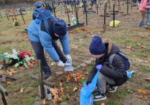 Uczniowie porządkują groby.