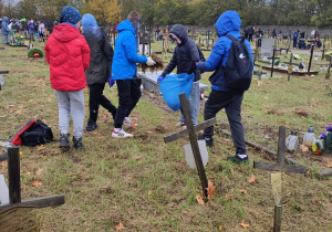 Uczniowie porządkują groby.